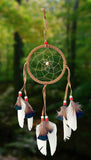 4-1/2" diameter ring dreamcatcher wrapped in tan leather and with tan leather straps and white feathers with brown & black tips and red and white beads on dark green background.