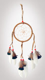 4-1/2" diameter ring dreamcatcher wrapped in tan leather and with tan leather straps and white feathers with brown & black tips and red and white beads on white background.