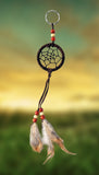 2" diameter ring wrapped in chocolate brown leather and adorned with leather straps and brown & white feathers. Accented with brick red and beige wooden beads on yellow sunrise sky.